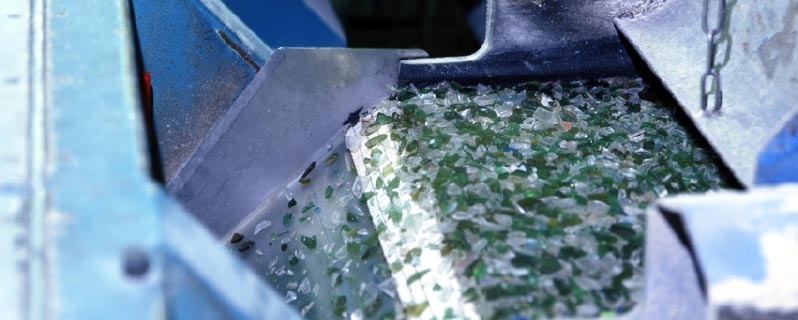 Förderband in der Recycling-Anlage mit zu winzigen Scherben zerbrochenem Glas