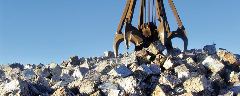 Zu Quadern gepresstes Material wird mittels Greifer in die Recycling-Anlage befördert